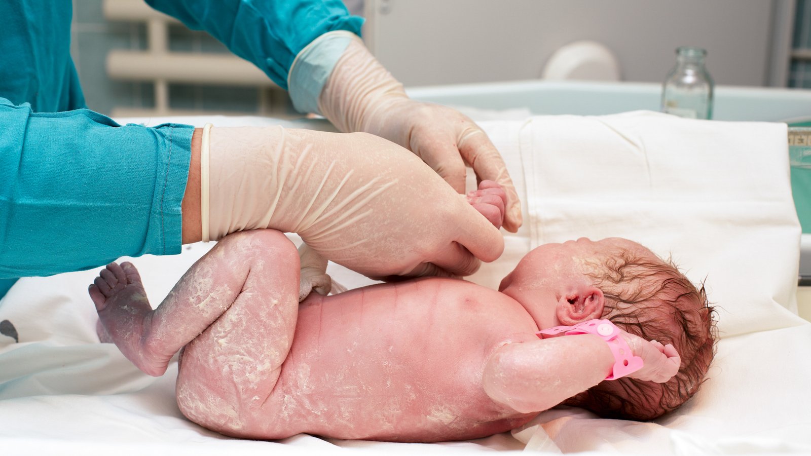 Newborn baby receiving a routine medical examination from a healthcare professional.