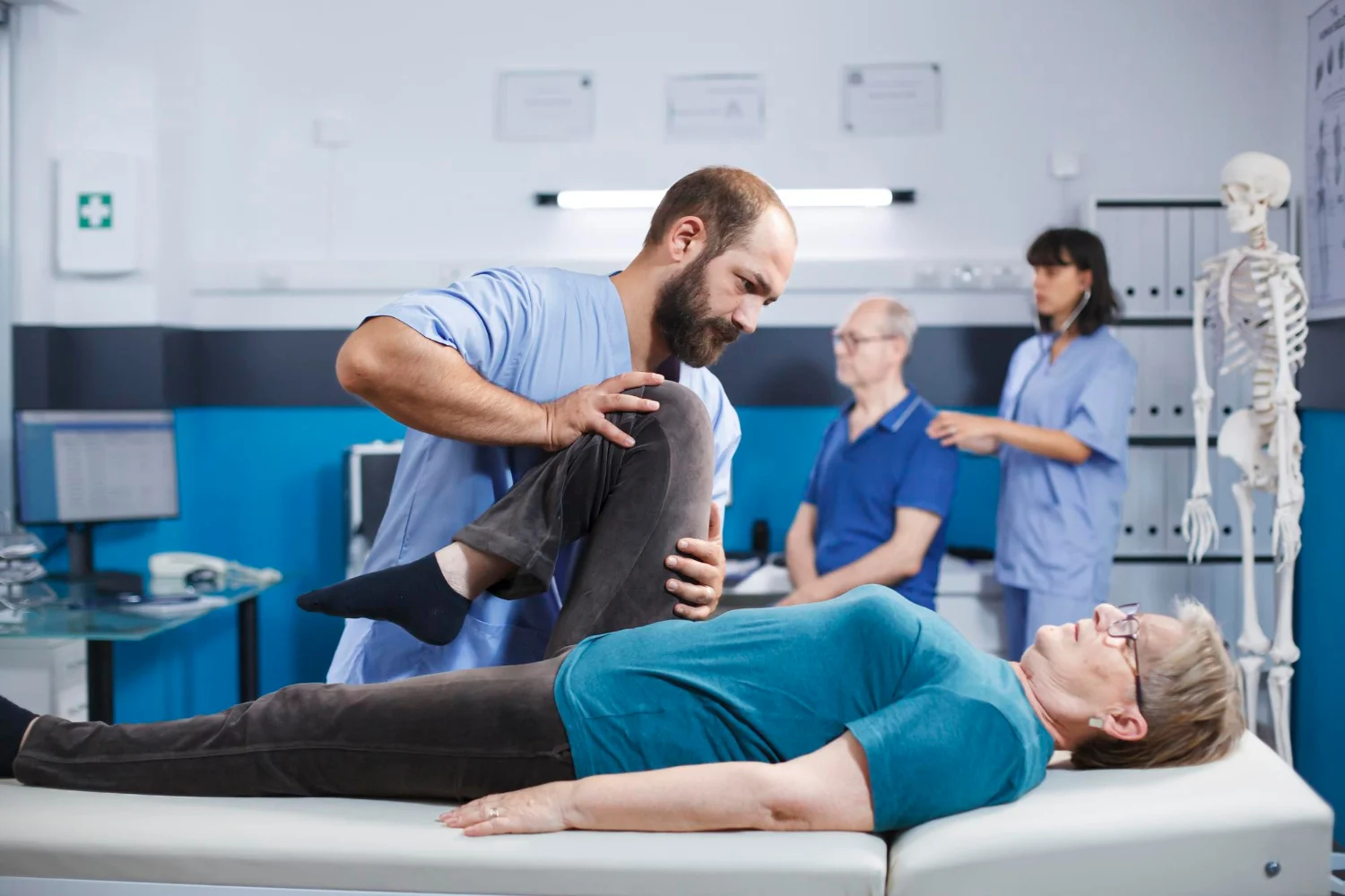 Physiotherapist helping an elderly woman perform a knee and leg rehabilitation exercise in a clinical setting.