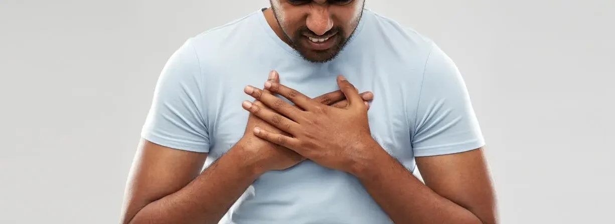 Man experiencing chest discomfort and holding his chest due to possible breathing or heart-related pain.