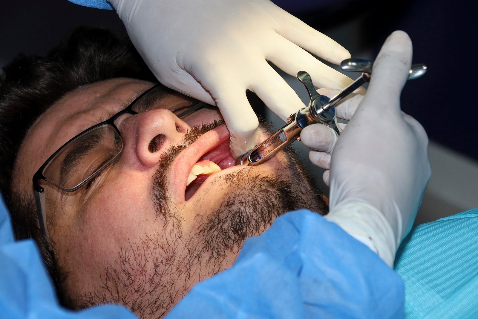 Dentist administering a dental injection to a patient during a dental treatment procedure.