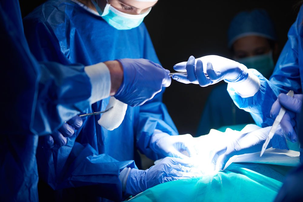 Surgical team performing a procedure in a hospital operating room using sterile instruments and medical equipment.