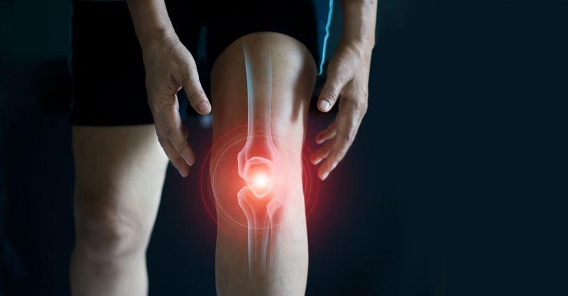 Person holding a painful knee joint highlighted with a red glow indicating knee pain or inflammation.