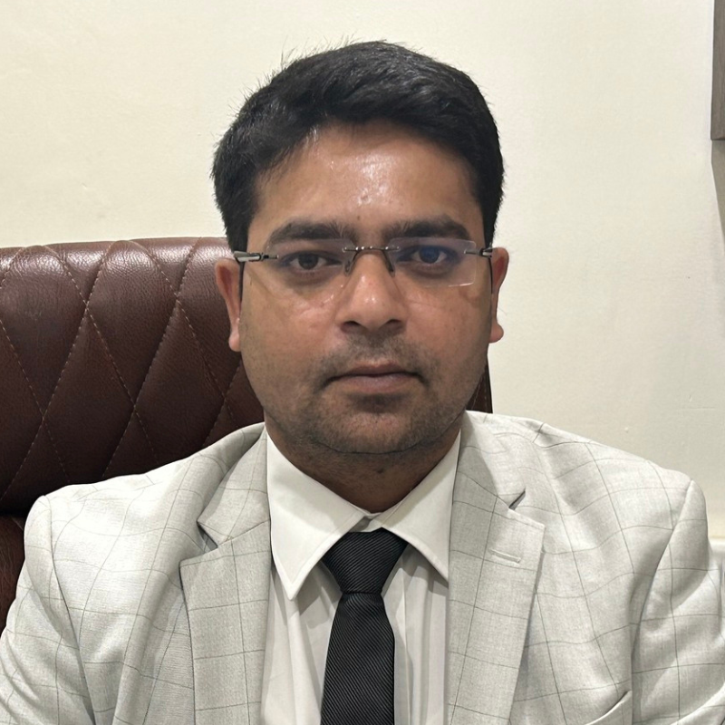Professional portrait of a male neurologist wearing glasses, formal attire, and seated in a hospital office.